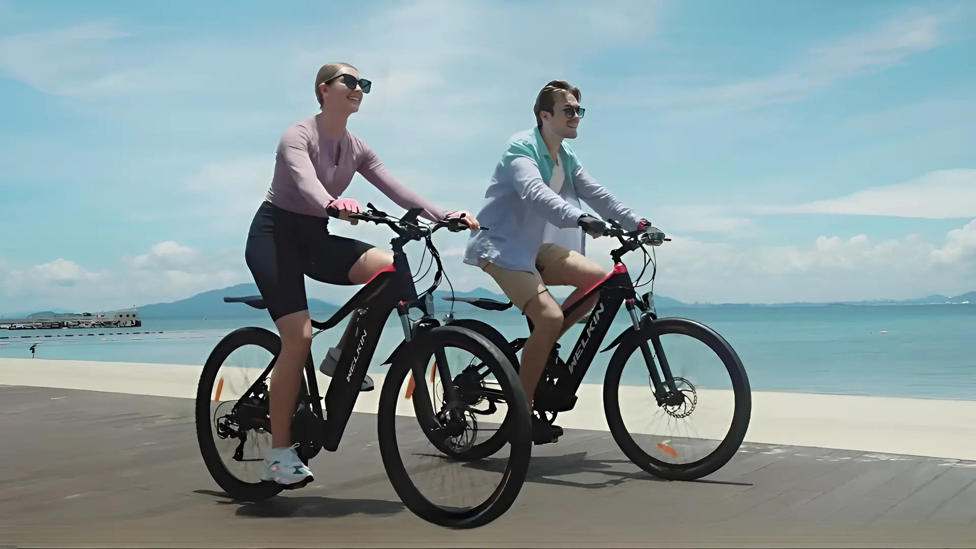 Yung couple riding WELKIN electric bikes on seaside