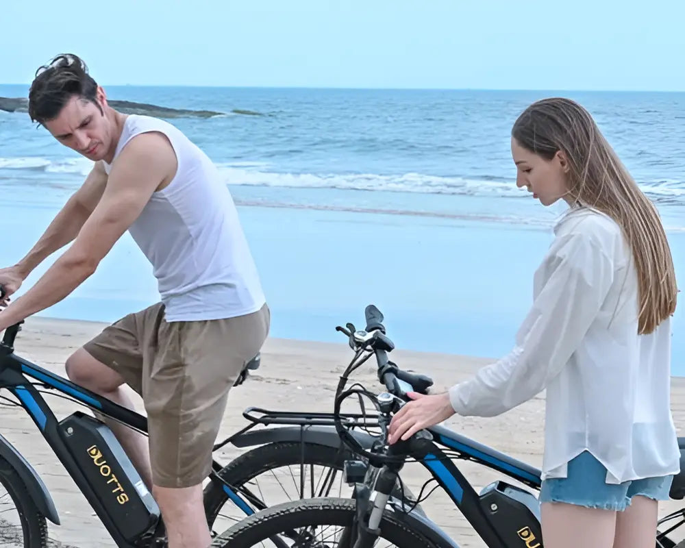 Young coulpe riding DUOTTS C29 PRO Electric Bikes on the beach